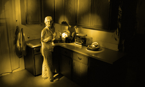 image of woman in pajamas in a dark kitchen